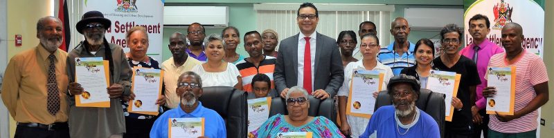 Housing and Urban Development Minister, Randall Mitchell flanked by the Certificate of Comfort recipients and Ossley Francis, Chairman, Land Settlement Agency (left) and Hazar Hosein, Chief Executive Officer, Land Settlement Agency (second from right).